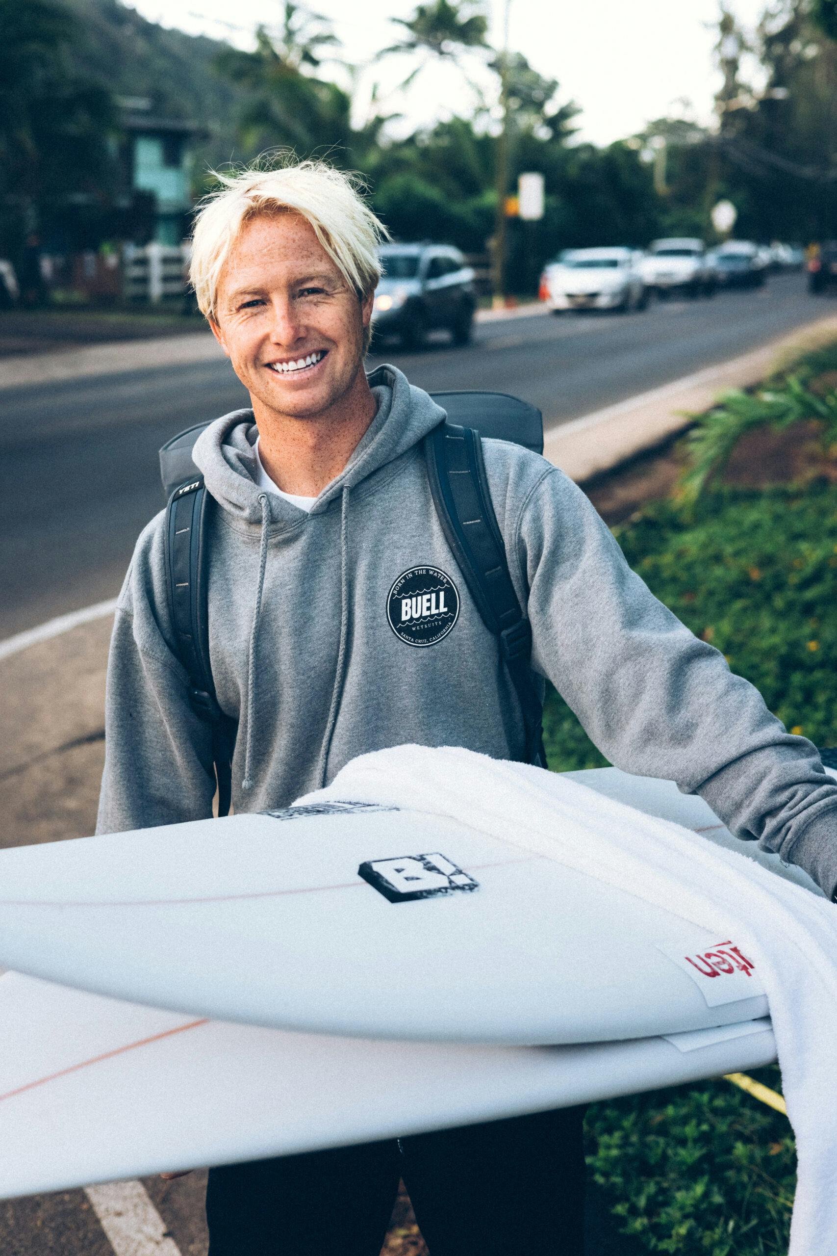 Nat Young carrying a couple surfboards
