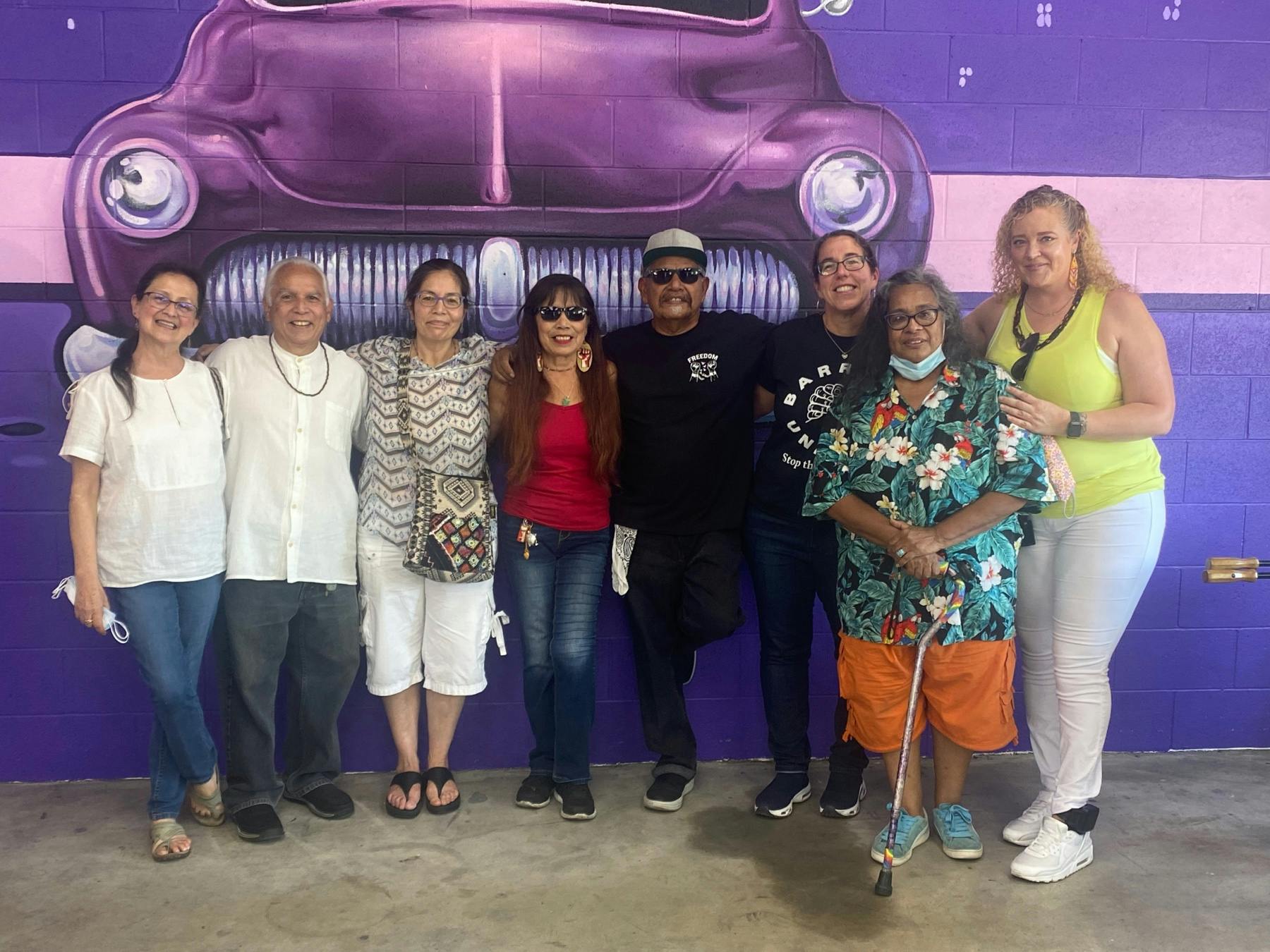 Members of Barrios Unidos stand together in front of mural