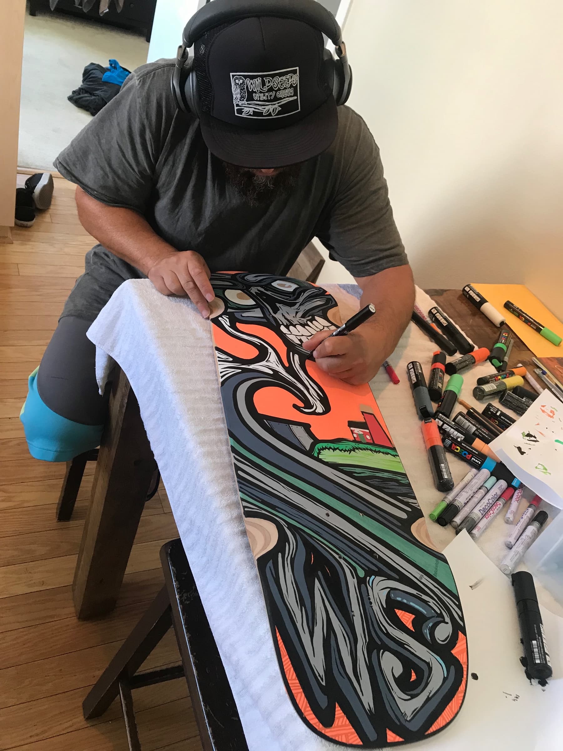 Jason "Willz" Williams draws a design on the bottom of a skateboard deck