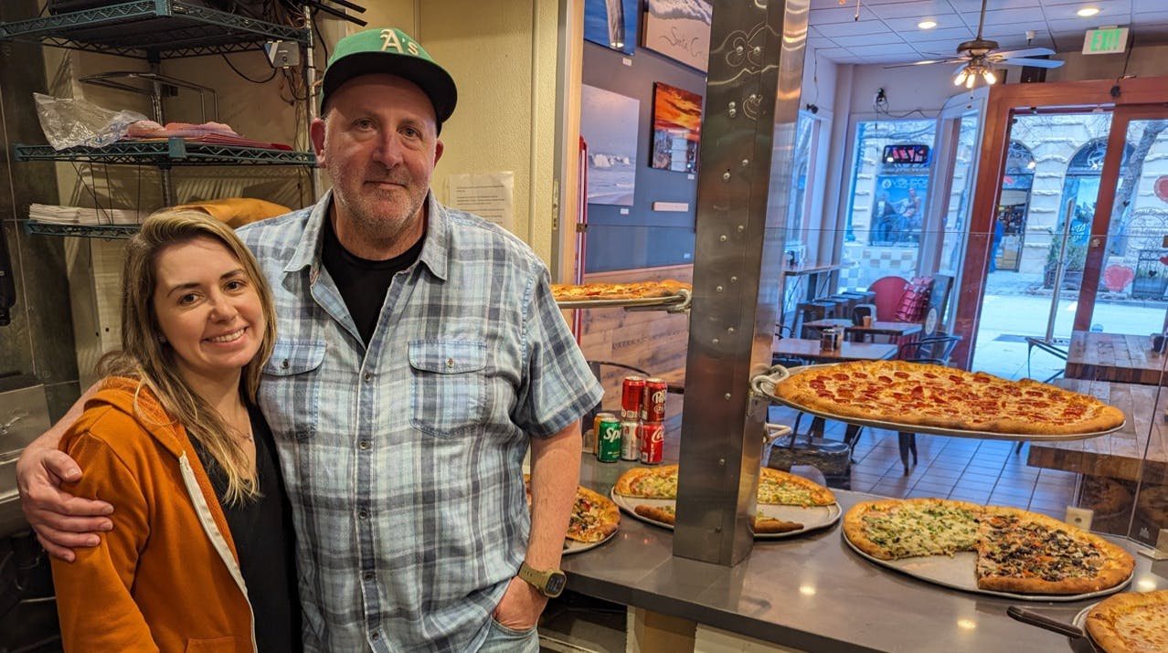 Sol Lipman and his partner, Eric, owners of Pleasure Pizza in Downtown Santa Cruz stand behind the counter full of pizza by the slice