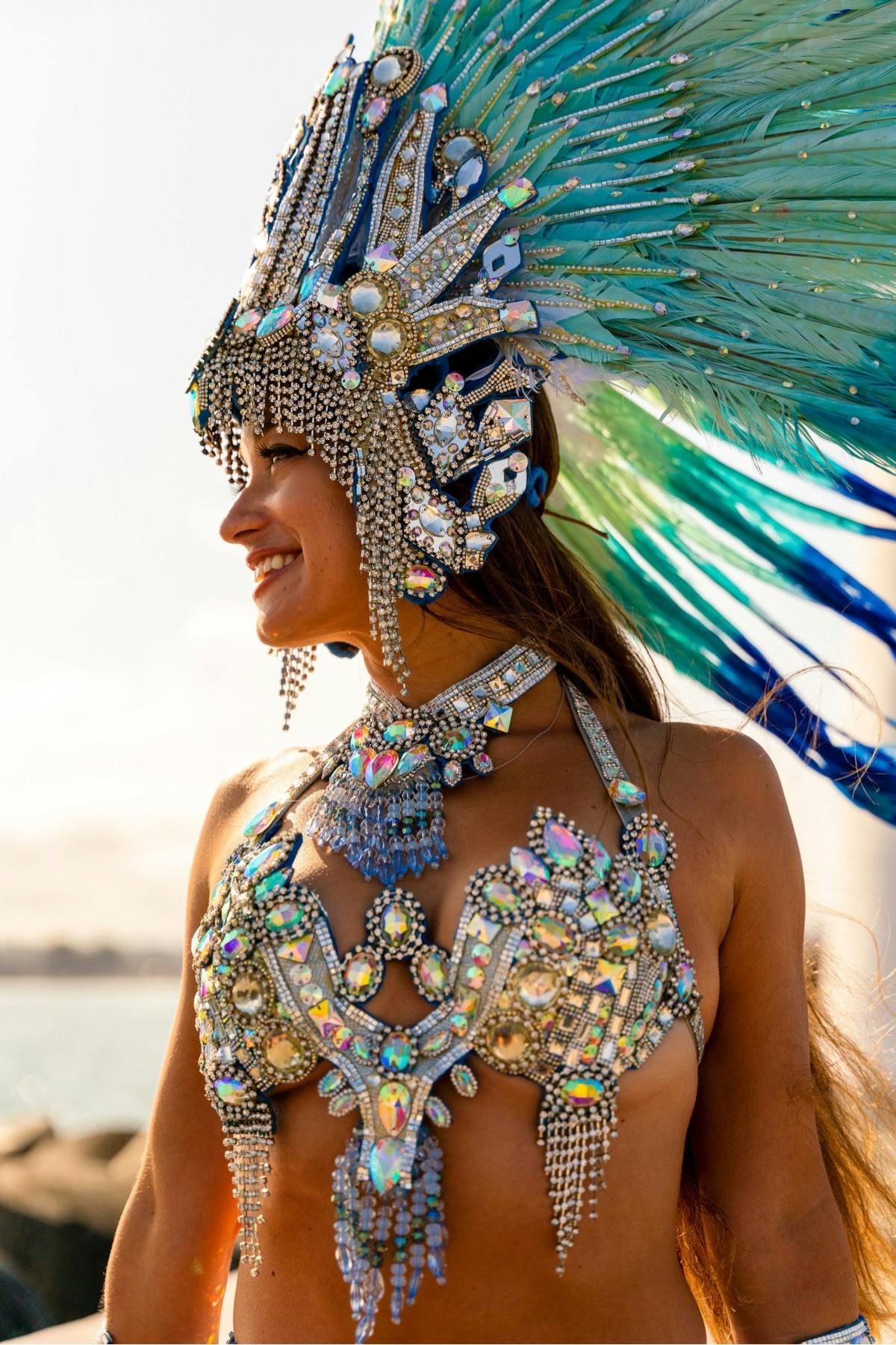 Gisella Ferreira smiles while dressed in samba attire including large feathered head dress