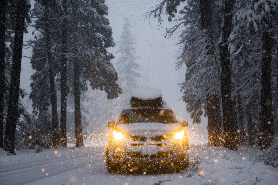 A front view of a vehicle with headlights on in a snowy Yosemite National Park